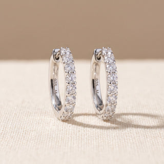 Slim shared prong moissanite huggie hoop earrings shown on model