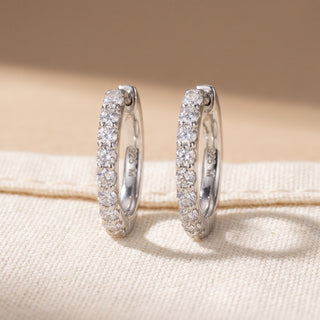 Slim shared prong moissanite huggie hoop earrings shown on model, side angle