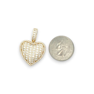A gold heart-shaped pendant paved with small clear stones, shown next to a US quarter coin for scale, on a plain white background.