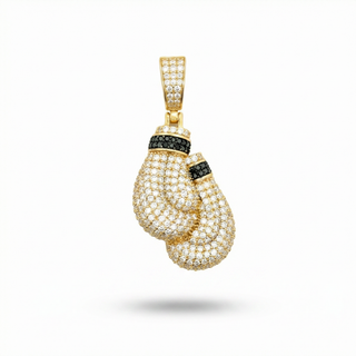A gold pendant shaped like a pair of boxing gloves, heavily embellished with small clear pavé stones and accented with black stones, shown on a white background.