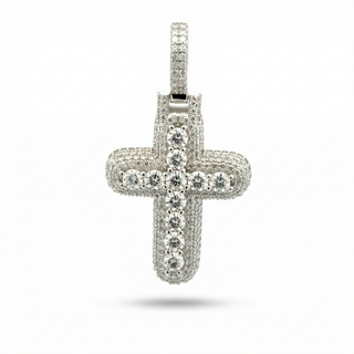 A silver cross pendant encrusted with clear gemstones, shown against a plain white background with a soft shadow underneath.