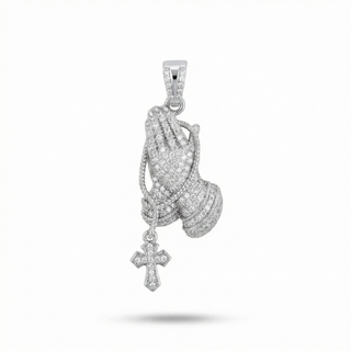 A silver-toned praying hands pendant covered in small clear stones, with a dangling cross charm, shown on a plain white background.