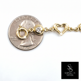 10K yellow gold heart link bracelet shown next to a quarter for size