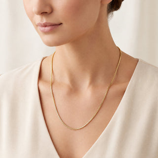 Superior Silver 18-inch 10K yellow gold box link chain worn around a woman's neck, featuring a delicate square weave.