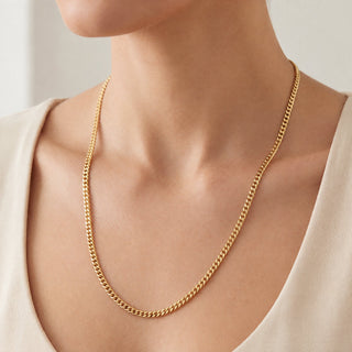 Superior Silver 24-inch curb link chain in 14kt yellow gold over 925 sterling silver worn around a model's neck.