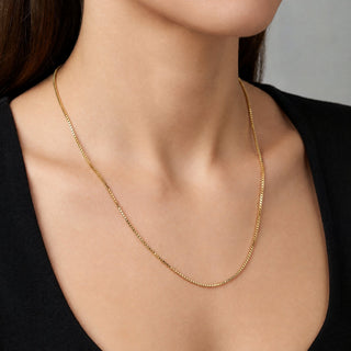 Superior Silver 10K yellow gold diamond-cut box link chain necklace worn on a model against a black top.