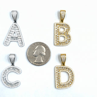 Superior Silver block initial pendants in sterling silver and gold with pave-set cubic zirconia stones next to a coin.