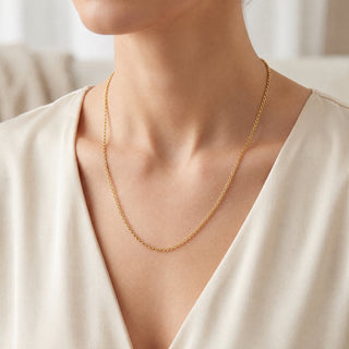 Superior Silver 20-inch 10K yellow gold cable link chain necklace worn on a model with a cream-colored top