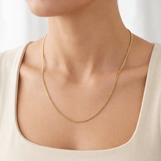 Superior Silver 10K yellow gold micro curb link chain necklace, 1.4mm wide, worn on a model's neck.