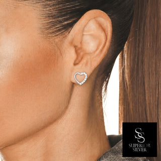 Open pavé heart outline moissanite stud earrings in sterling silver, worn on model