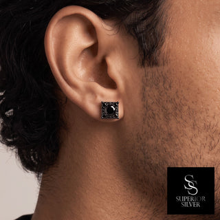 Square halo round solitaire moissanite stud earrings in black rhodium over sterling silver, worn on model
