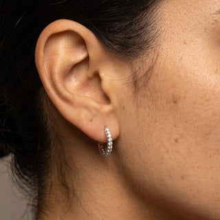 Model wearing 10mm sterling silver slim pave moissanite huggie hoop earrings