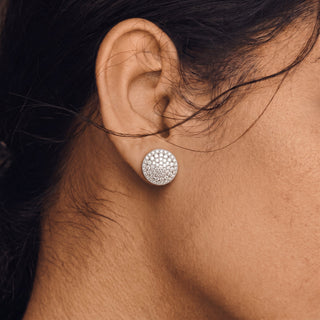 Model wearing sterling silver round pavé disc moissanite stud earrings, side angle