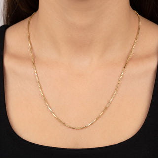 Superior Silver 24-inch 10K yellow gold box link chain with diamond-cut facets worn around a woman's neck.
