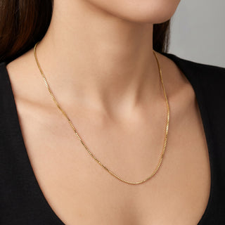 Superior Silver 10K yellow gold diamond-cut box link chain necklace worn on a model against a black top.