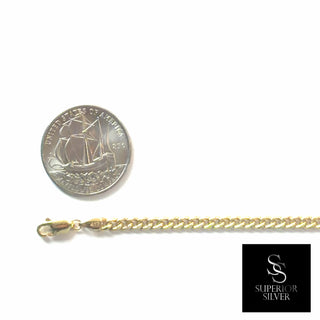 Superior Silver 10K yellow gold curb link bracelet with a lobster clasp, shown next to a coin for scale.