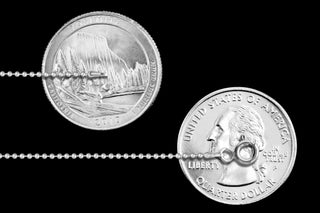 Superior Silver 1mm sterling silver bead chain shown next to US quarters for scale on a black background