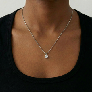 Necklace with a pendant on a person wearing a black top against a neutral background