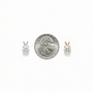 Two diamond earrings next to a quarter for size comparison on a white background