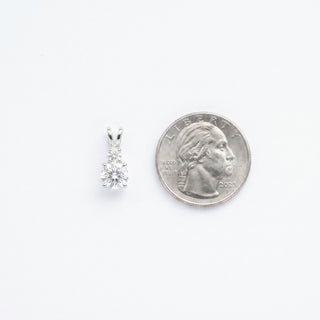 Superior Silver double drop round VVS moissanite pendant in 925 sterling silver next to a US quarter for scale