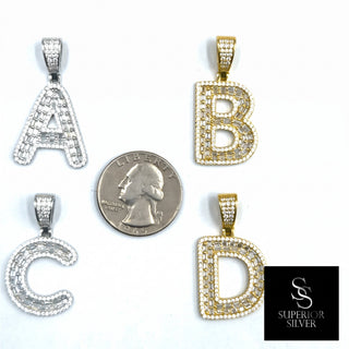 Superior Silver block initial pendants in sterling silver and gold with pave-set cubic zirconia stones next to a coin.