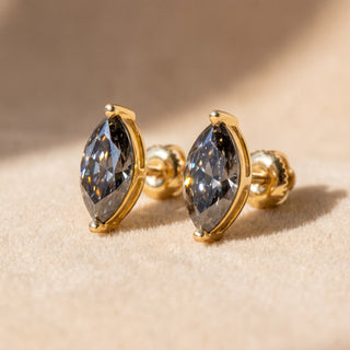 Superior Silver marquise cut moissanite stud earrings in yellow gold with secure screw backs on a soft beige surface.