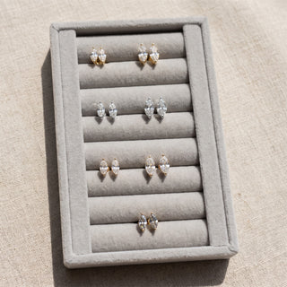 Superior Silver marquise moissanite stud earrings in white, yellow, and rose gold finishes displayed on a grey tray.