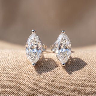 Superior Silver marquise cut moissanite stud earrings in sterling silver with secure screw backs on a textured surface.