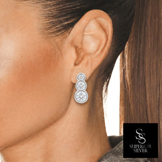 Three stone bezel climber moissanite stud earrings in sterling silver, worn on model