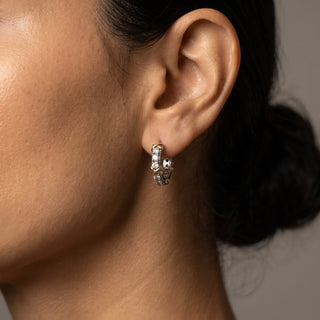 Two tone 10mm slim moissanite X motif huggie hoop earrings shown on model, side angle